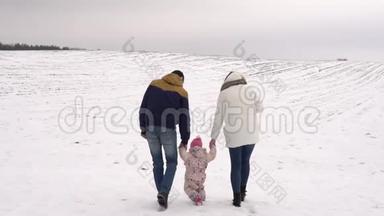 爸爸妈妈被教导在雪地里走我的女儿。 冬季家庭步行