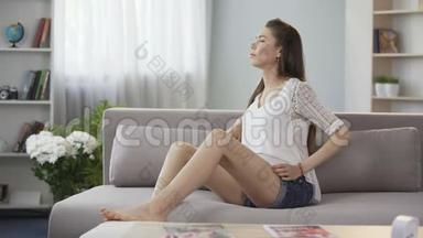 孕妇坐在沙发上搓揉下背部，<strong>孕期</strong>背痛