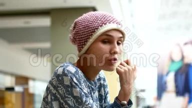 一个年轻的女人在商场里吃一个多汁的绿色苹果。 健康零食的概念