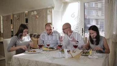 四个朋友在餐厅，吃肉喝<strong>红酒</strong>在<strong>杯子</strong>里。
