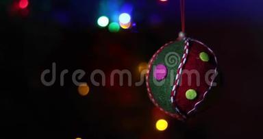 猫在云杉树枝上玩圣诞软玩具。 背景是多种颜色的圣诞彩灯花环
