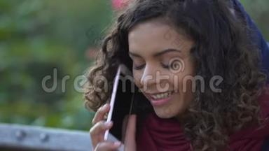 快乐的混血女人在户外谈论智能手机，微笑着结束电话