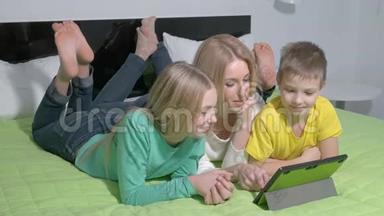 漂亮的年轻家庭在卧室里用平板电脑