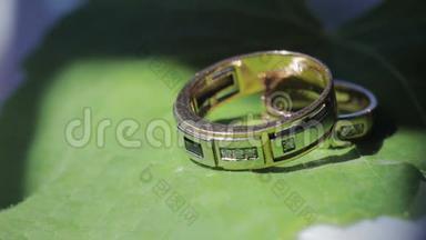 结婚戒指躺在绿叶床单上，特写