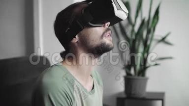 年轻留胡子的嬉皮士用他的VR耳机显示虚拟现实游戏或观看360视频，并正在。