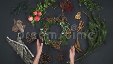 头顶的人手拿花环在文字复制空间上。 带有天然叶子、松树的深色桌子的垂直俯视图