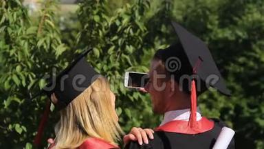 几位快乐的毕业生在智能手机上录制视频，毕业典礼