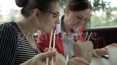 两个年轻的商务女孩午餐吃<strong>中国</strong>面条，喝咖啡，考虑到生意的<strong>发展</strong>