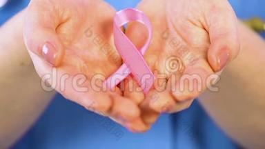 女人在<strong>手心</strong>轻轻地握着粉红色的丝带，支持患有乳腺癌的女人