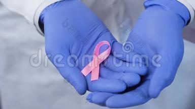 双手戴手套小心地拿着粉红色的丝带，象征着乳腺癌的意识