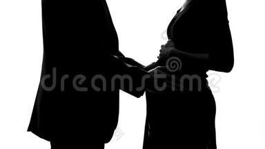 孕妇的影子和慈爱的丈夫抚摸她的腹部，计划生育