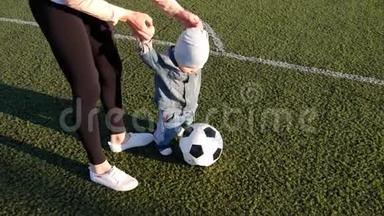 小男孩和他妈妈在足球场上<strong>踢</strong>足球。