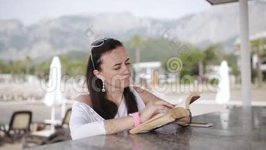 在大自然中阅读。 女人一边看书一边站在海边码头的酒吧..