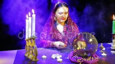一个穿着红衣服戴围巾的吉普赛人把卡片放在蜡烛的倒影里