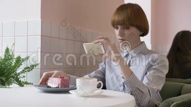 年轻漂亮的红发女孩坐在咖啡馆里做蛋糕的照片。 今天的问题，社交网络。 60英尺
