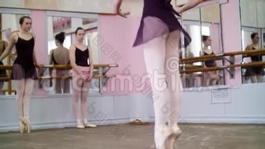 在舞厅里，穿着黑色紧身衣的年轻芭蕾舞演员在止血带上表演滑翔，她在芭蕾舞课上<strong>走动</strong>