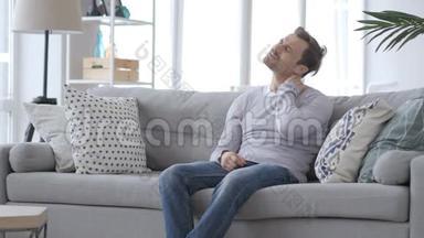 疲劳的成年男子，<strong>颈部</strong>疼痛坐在沙发上，试图放松