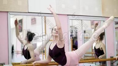 在舞厅里，穿着紫色紧身衣的年轻芭蕾舞演员优雅地表演着某种芭蕾舞动作，气势恢宏