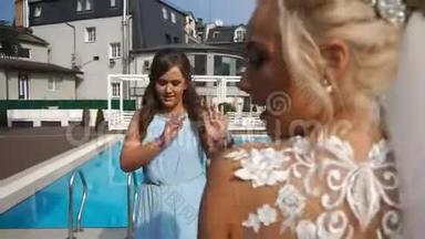 迷人的新娘在游泳池附近和伴娘跳舞时玩得很开心。 结婚纪念日。