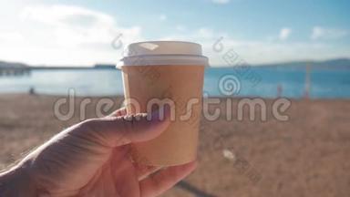 游客拿着一杯热咖啡靠在海滩和蓝海上。 旅游与旅游理念。