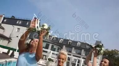 美丽微笑的金发新娘和漂亮的伴娘们正在空中投掷婚礼花束，并在附近<strong>接住</strong>