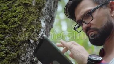 生态学家研究树木上的苔藓，并将数据写入平板电脑。