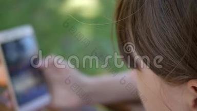 一个使用智能手机的年轻女孩正在公园的一家网上商店里的长凳上<strong>翻页</strong>。 年轻的千禧年