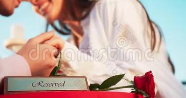 浪漫的构图。 在这对温柔相爱的夫妇模糊的背景下，桌子上保留着匾额和红玫瑰