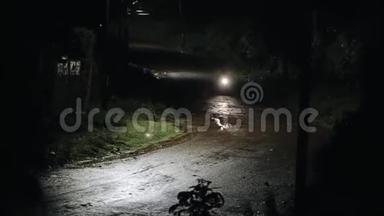 摩托车手在雨中深夜骑在一条潮湿的路上。 看雨和灯。