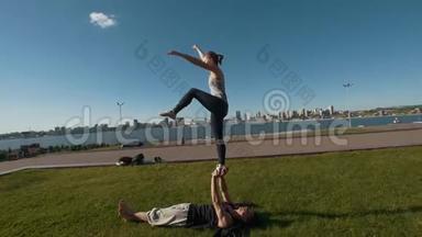 年轻的情侣练习杂技表演前木板鸟姿势，年轻男子抱着飞行女子平衡