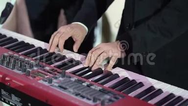 音乐家演奏电子键盘合成器钢琴。 乐队在音乐会舞台上演奏音乐
