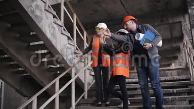 工程师和两名女检查员在现场施工或恢复现场检查楼梯间，并讨论有关细节