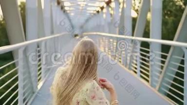 女人<strong>回头看</strong>桥。 漂亮的金发女郎<strong>回头看</strong>镜头，一边在桥上奔跑，留着波浪发。