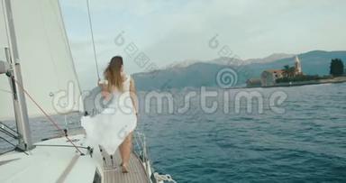 在游艇上的<strong>女士</strong>。 一个穿着白色<strong>长裙</strong>的女人站在船上，在一个多风的天气里骑过湖面