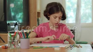坐在桌边用<strong>彩色铅笔画</strong>画的小女孩