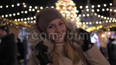 穿着温暖衣服微笑的女人，站在圣诞市场上照明