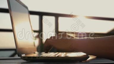 一个女人在工作场所用笔记本<strong>电脑打字</strong>。 夕阳下的女孩。 电子网上购物