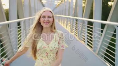 女人<strong>回头</strong>看桥。 漂亮的金发女郎<strong>回头</strong>看镜头，一边在桥上奔跑，留着波浪发。