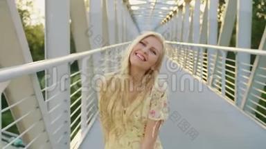 女人回头看桥。 漂亮的金发女郎回头看镜头，一边在桥上奔跑，留着波浪发。
