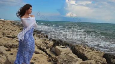 美丽的年轻女子，心情浪漫，站在海边，望着风浪