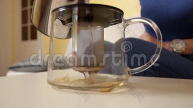 一个年轻的女孩在一个特殊的茶壶里倒水来泡茶。 冲泡茶。 <strong>茶饮</strong>