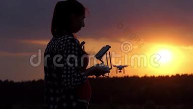 明亮的女人拿着一个面板在太阳落山时操作她的无人机