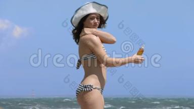 穿比基尼的年轻女子在海边的海滩上晒太阳，在身上涂上<strong>防晒</strong>霜
