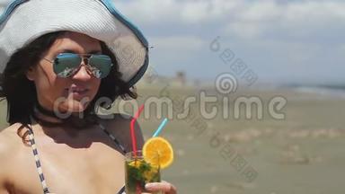 戴着墨镜和帽子的贴身美女，在海滩上喝了很久