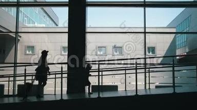 母亲和小女儿的剪影，在大窗户的背景下走下机场的<strong>大门</strong>