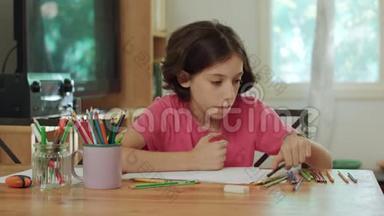 坐在桌边用彩色铅笔画画的小女孩