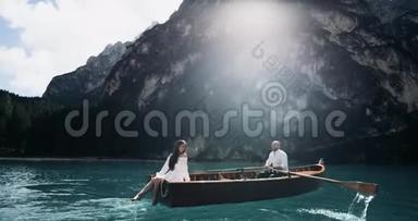 浪漫的<strong>情侣</strong>在湖中央的木船上做特写，男人正在<strong>划船</strong>，他的女朋友在玩腿