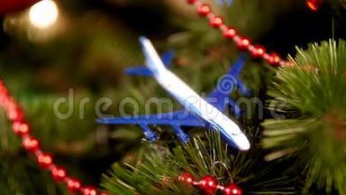特写4k视频的微型飞机躺在圣诞树上发光的彩色灯光。 旅行的概念
