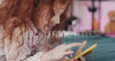 有趣<strong>的</strong>红头发小女孩与黄色智能手机躺在床上和使用智能手机。 沟通，播放，<strong>APP</strong>..