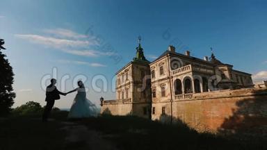 迷人的新婚夫妇的剪影<strong>轻轻地</strong>亲吻着古老城堡的背景。